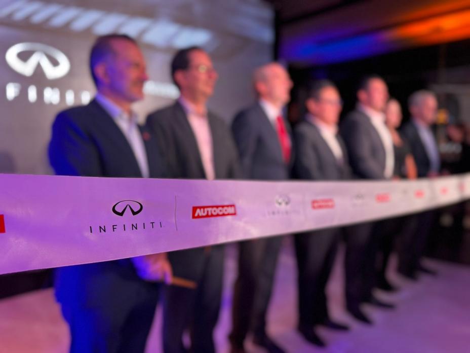 Cinta con los logotipos de INFINITI y AUTOCOM en primer plano durante la ceremonia de corte de listón en la inauguración de INFINITI Universidad, con fondo iluminado y escenario institucional.