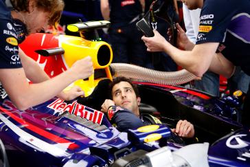 Infiniti driver speaking to his team while sitting in Red Bull race car.
