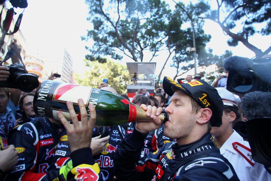 Un homme célébrant sa victoire au Grand Prix de Monaco en buvant une grande bouteille de Champagne