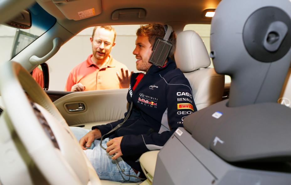 Sebastian Vettel sitting in a car with a man outside talking to him