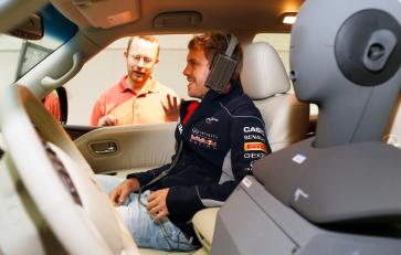 Sebastian Vettel sitting in a car with a man outside talking to him