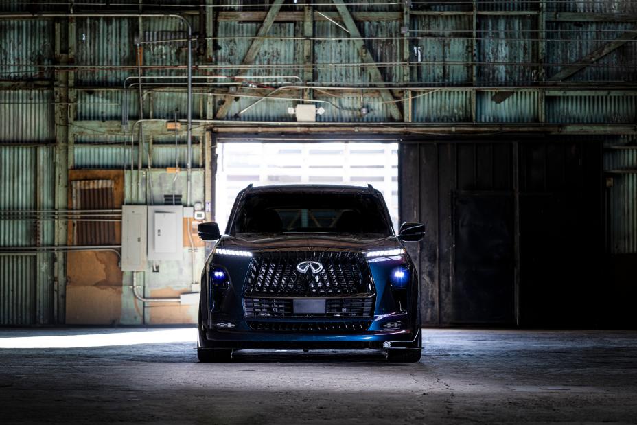 Front view of the QX80 R-Spec build parked inside a warehouse with the headlights iluuminated.