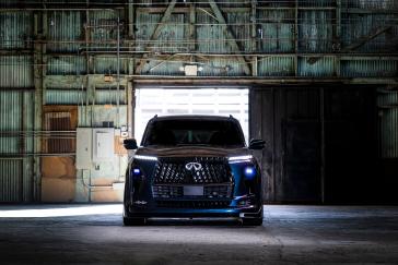 Front view of the QX80 R-Spec build parked inside a warehouse with the headlights iluuminated.