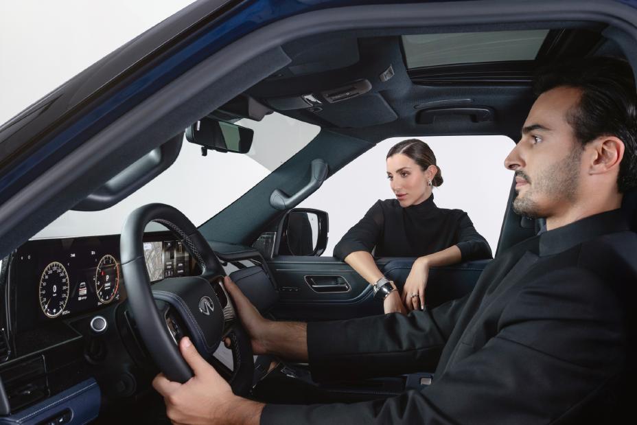 Full side view of one person seated inside an SUV while another stands outside looking in