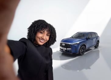 Close-up of person taking a selfie with the QX60S in the background