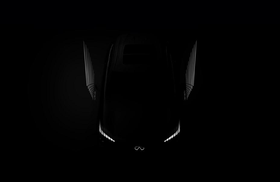 A car is dimly lit only leaving the illuminated INFINITI logo and headlights visible.