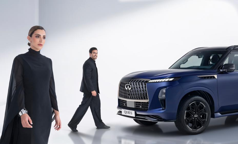 Side view of two people walking alongside the QX80S