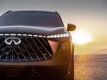 Vue partielle de l’avant du QX65 Monograph au coucher du soleil, avec les phares allumés.